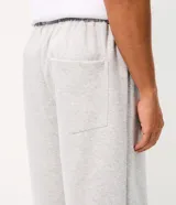 Pantalón de corte super baggy confeccionado en tejido de algodón y poliéster, color gris melange. Presenta un diseño urbano con estampado de serpiente tribal en color negro en las piernas, cintura elástica y bolsillos laterales.