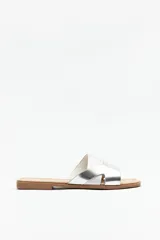 Sandalias bajas de símil cuero con capellada texturizada y entrelazada en color negro y gris oscuro, de suela plana.
