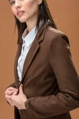 Blazer de corte clásico y estructurado en color marrón con textura de espiga. Presenta solapas tradicionales, cierre frontal y mangas largas.