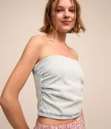Top de jean celeste, sin breteles, con escote recto y cierre trasero.