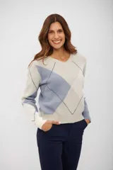 Sweater de punto con cuello en V y diseño de rombos en tonos beige, azul y blanco. Presenta mangas largas con puños ajustados y corte clásico.