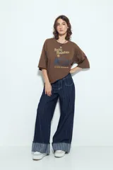 Remera blanca de manga corta con calce relajado y cuello a la base. Presenta un estampado frontal pequeño y una estampa protagonista en la espalda con el texto "Rocky Mountain National Park" y un paisaje de montañas y árboles.