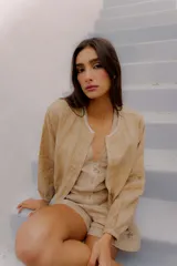 Campera bomber de lino color tostado, con cierre frontal y detalles de costura decorativa en el escote.