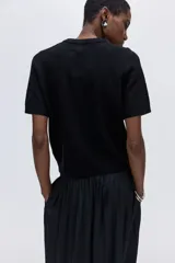 Buzo de punto fino suave con cuello redondo y mangas cortas. Presenta terminaciones acanaladas en el cuello, los puños y el bajo.