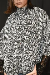 Campera bomber oversize de paño italiano con estampado en zigzag blanco y negro, cuello alto y cierre frontal con broches a presión. Tiene mangas murciélago.
