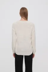 Sweater de punto color crudo, con cuello redondo y mangas largas.