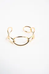 Brazalete rígido abierto de metal dorado con diseño de eslabones ovalados entrelazados.