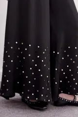 Pantalón amplio de viscosa y modal, color negro, con cintura elastizada y lentejuelas doradas aplicadas en la parte inferior de las botamangas.