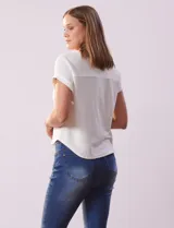 Remera blanca de tejido ribs con cuello a la base y escote en V. Tiene dos bolsillos aplicados en el frente y mangas cortas con dobladillo.