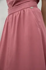 Falda midi color rosado, de corte en A, con cintura fruncida elástica y abertura frontal.