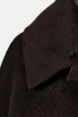 Abrigo confeccionado en hilatura con lana, de corte recto y diseño minimalista. Presenta cuello solapa con aplicación de pelo sintético desmontable, cierre frontal con botones y bolsillos de plastrón en el delantero.