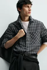 Camisa de corte relajado confeccionada en voile de algodón, con estampado de cuadros. Presenta cuello solapa, manga larga con puños abotonados, bolsillo de parche en el pecho y cierre frontal de botones.