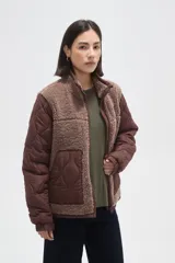 Campera de diseño híbrido que combina paneles de corderito sintético en color crema con mangas y bolsillos de tela técnica acolchada en color verde militar. Presenta cierre frontal completo, cuello alto y un pequeño parche decorativo en el pecho.