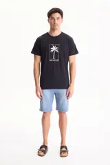 Remera negra de manga corta y corte regular fit, confeccionada en algodón, con estampa frontal que presenta una palmera dentro de un rectángulo punteado y la inscripción 'palm tree dream'.