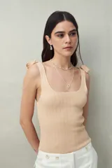 Top blanco tejido con tiras para anudar en los hombros y diseño tramado.