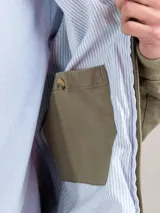 Campera Harrington color beige, con cuello alto abotonado, cierre frontal completo y bolsillos laterales con solapa y botones a presión. Puños y cintura elastizados de rib.