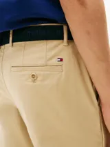 Pantalón corto tipo bermuda de sarga de algodón elástico, color beige, con cierre de cremallera, bolsillos delanteros y traseros, e incluye cinturón con detalles distintivos.