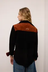 Sobrecamisa de gamuza color marrón con apliques de cuero metalizado en tono cobre en los hombros y bolsillo frontal. Presenta detalles bordados en las mangas, el bolsillo y la espalda, con un diseño de corte recto y cuello camisero.