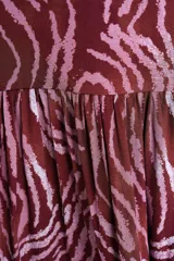 Vestido largo bordó con estampado animal print abstracto en tonos rosados, con cuello halter y falda escalonada con volados.