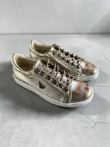 Sneakers de cuero dorado con cordones, suela blanca de goma y detalles pintados a mano en la puntera por la artista Carolina De Cunto.