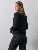 Chaqueta negra en tejido tweed de la marca Nanette. Tiene escote mao, abertura central y bolsillos delanteros. Los puños tienen apliques de botones perlados y la terminación es desflecada. Tiene forro interno.