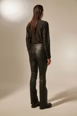 Pantalón negro de efecto cuero, tiro medio, con corte recto y ligeramente acampanado en la parte inferior.