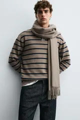 Polo de punto de manga larga con cuello solapa y cierre frontal de botones. Presenta un diseño de corte regular con aberturas laterales en el bajo.