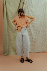 Pantalón de corte ancho y silueta abombada, color gris claro, con bolsillos frontales y costuras decorativas verticales.