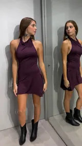 Vestido corto bordó con cuello halter y diseño sin mangas, de corte ajustado en el torso y falda con caída asimétrica.