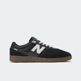 Championes New Balance modelo 508 de color negro, con detalles en blanco y suela de goma marrón. Combinan malla y gamuza, con el característico logo "N" en los laterales y cordones blancos.