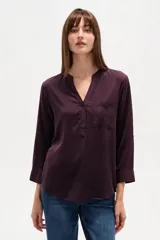 Blusa de viscosa color bordó, con cuello en V, cierre frontal parcial con botones, mangas tres cuartos y bolsillo aplicado en el pecho.