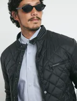 Campera capitoneada de color azul oscuro, con cierre frontal de metal y botones a presión. Presenta bolsillos laterales y en el pecho con cierres metálicos.