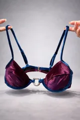 Top de bikini de terciopelo color bordó con ribetes y tirantes en azul. Cuenta con aros y un estribo metálico en el centro.