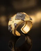 Anillo ancho de bronce con baño de oro y acabado texturizado, decorado con un diseño central geométrico de circonias incrustadas y detalles en los extremos.