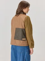Campera de diseño híbrido con frente acolchado en color tostado, solapas y cuello en tejido de lana con patrón de cuadros tipo príncipe de gales, y mangas en paño de lana color azul marino. Cuenta con cierre frontal de botones.