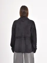 Campera de textura afelpada en color negro, con cierre frontal de botones a presión, cuello camisero y bolsillos frontales con solapa.