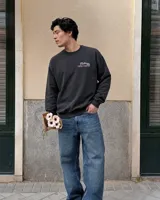 Buzo negro de cuello redondo y manga larga, de corte regular fit. En la espalda presenta un estampado gráfico en color blanco y rosa con la leyenda "Fletes" y el dibujo de una grúa transportando una planta.