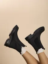 Botas tipo Chelsea de color negro con suela track de plataforma, paneles laterales elásticos y cierre lateral interno.