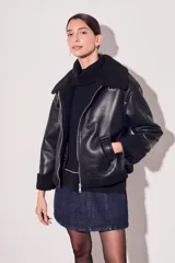 Campera negra de cuero sintético con cuello y puños de piel sintética. Corte oversize y cierre frontal con cremallera.