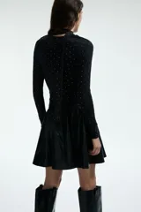 Remera de manga larga en punto elástico, color negro con estampado de lunares pequeños en color blanco. Presenta un diseño entallado con cuello drapeado y una tira lateral decorativa.