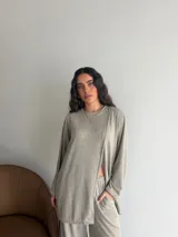 Conjunto de dos piezas color gris melange, confeccionado en tela de lanilla, compuesto por un buzo de manga larga con diseño cruzado al frente y un pantalón largo de corte holgado y tiro alto.