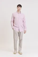 Camisa de manga larga, color rosa claro con finas rayas verticales blancas, cuello camisero y un bolsillo en el pecho.