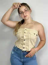Top strapless color beige con botones plateados al frente y dos bolsillos pequeños.