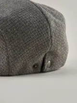 Boina de estilo clásico confeccionada en tejido de lana gris melange, con etiqueta decorativa de la marca Benson & Thomas en el lateral.