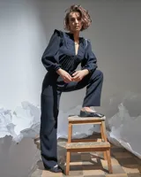 Mono largo negro de acetato con mangas largas abullonadas con elástico en los puños, detalle de raso en hombros y cinturón, escote en V regulable con cierre invisible y textura plisada artesanal en el frente superior.