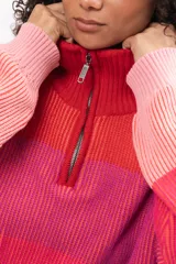 Buzo de tejido de punto con diseño a rayas horizontales en tonos degradados de rojo y rosa. Presenta cuello alto con cierre frontal parcial, mangas largas y corte holgado.