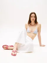 Ojotas color coral con tiras de textil trenzado y suela plana.