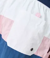 Bermuda de baño para hombre, color azul con recortes en bloques de color (azul más claro y rosa pálido). Presenta cintura elástica con cordón de ajuste y es de tejido plano de poliamida.