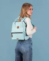 Mochila Cabaia modelo Adventurer en color turquesa claro. Cuenta con un compartimento principal con cierre, un bolsillo frontal con cierre y detalles en cuero sintético marrón, incluyendo parches con el logo de la marca. Posee asas superiores para llevar en la mano y correas ajustables para los hombros.