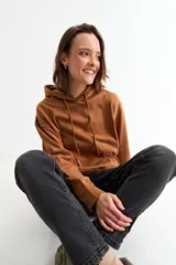 Canguro con capucha y cordones ajustables, de diseño liso y corte holgado con bolsillo frontal tipo canguro.